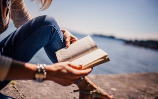 A person sitting on the ground reading a book.