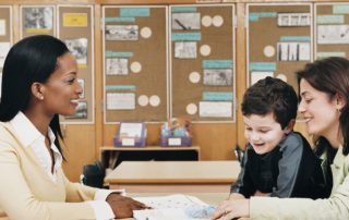 A woman and boy sitting at table in classroom.