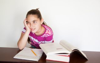 A girl sitting at her desk with books and pencils.