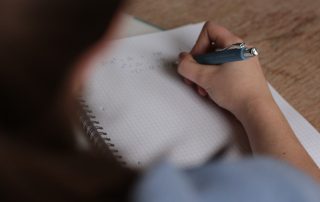 A person writing on paper with a pen.